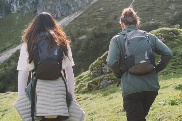 Scatto estivo di due escursionisti con zaini da trekking in look sportivo da dietro