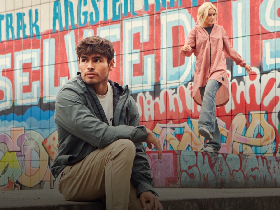 Una donna dall’aspetto giovane e un uomo dall’aspetto giovane in abbigliamento outdoor casual davanti a un muro con graffiti