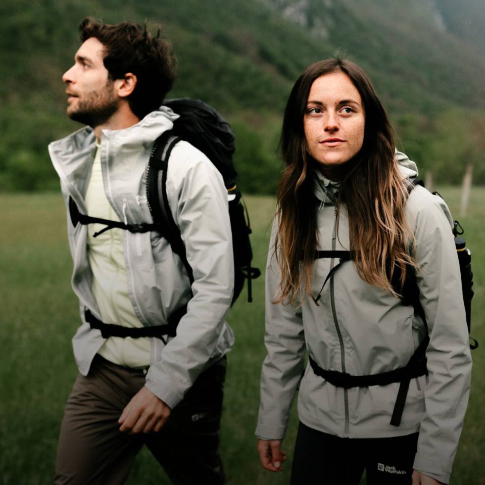  Donna e uomo in abbigliamento sportivo da trekking in un paesaggio montano verde