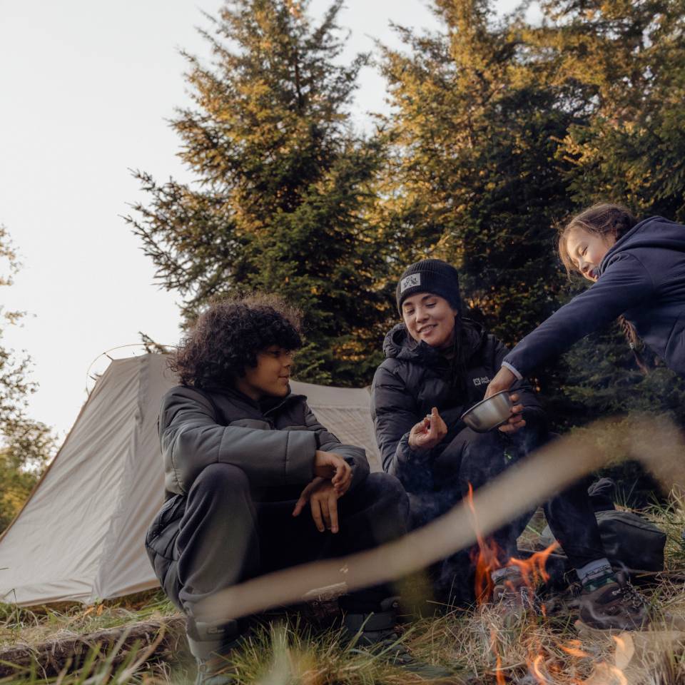 Drei junge Wanderer sitzen beisammen in herbstlicher Waldkulisse