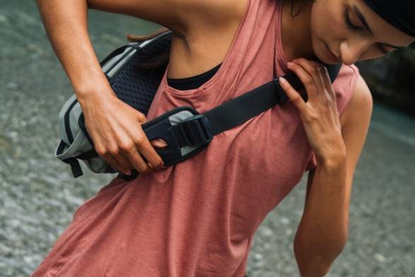 Giovane donna in abiti da trekking estivi e sportivi con una borsa a tracolla sportiva