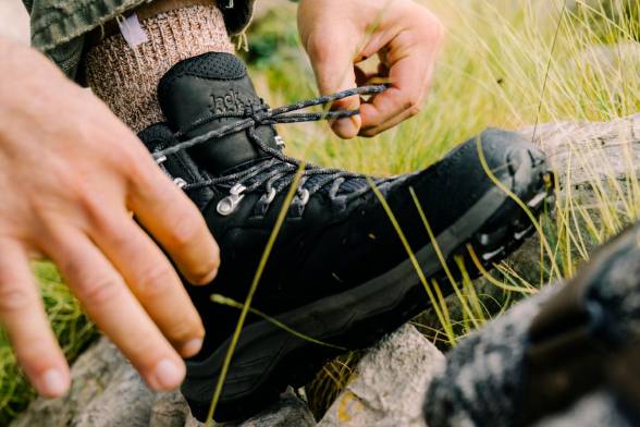 Primo piano di un uomo con scarpe da trekking nere che si allaccia le scarpe