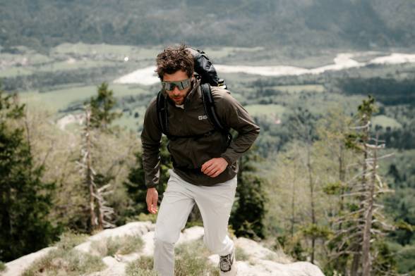 Uomo in abbigliamento sportivo da trekking e occhiali da sole in un paesaggio montano