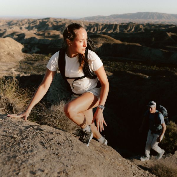 Frau und Mann in sommerlicher Outdoor-Kleidung klettern einen Felsen hinauf